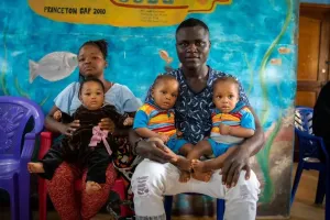 A man and a woman sit with 3 of their kids on their laps.