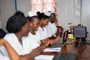 nurses sitting next to each other working on laptops
