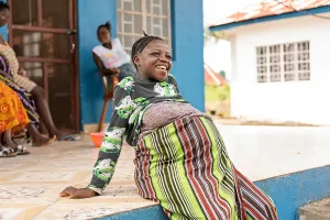 A pregnant woman sits outside a waiting home at a clinic