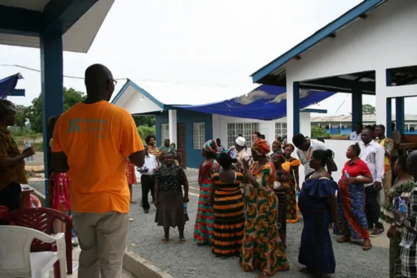 A man stands in front of a group of women as they wait for a ceremony to start.