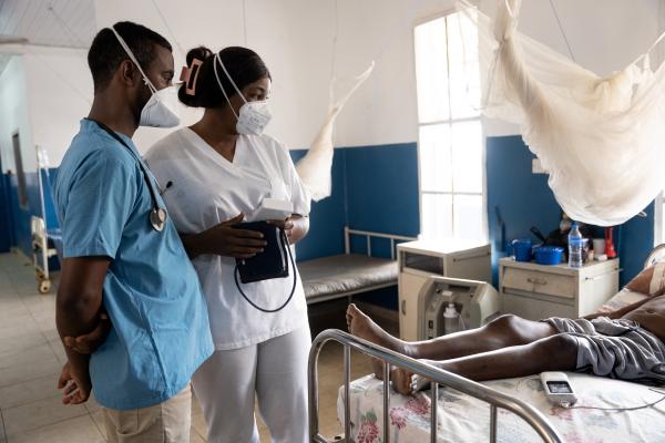 doctor and nurse stand next to patient bed