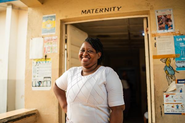 woman smiling at camera in front of door that reads maternity