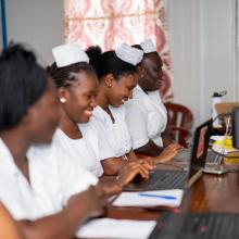 nurses sitting next to each other working on laptops