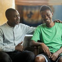 two men sitting next to each other smiling