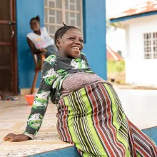 A pregnant woman sits outside a waiting home at a clinic