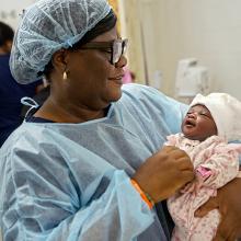 A clinician holds a newborn baby