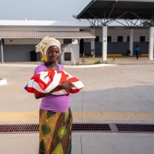 Jeneba Koroma holding a baby outside the MCOE