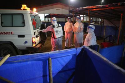 Four people in PPE prepare the triage area for the incoming ambulance