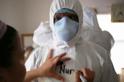 Man in PPE is getting "Nurse" written on his suite