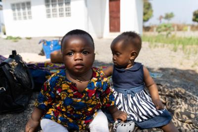 Two babies sit in the shade