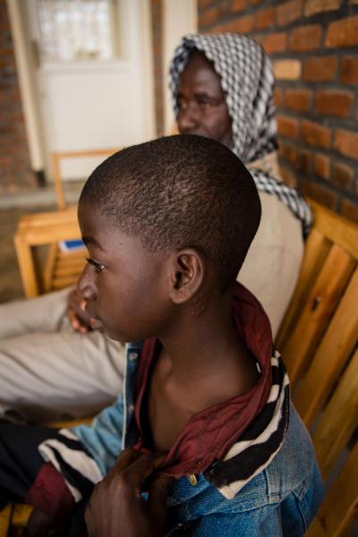 Mondeh sits on a bench with his father at Butaro Hospital