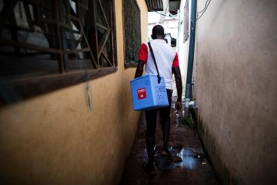 A man carries a cooler with the vaccine