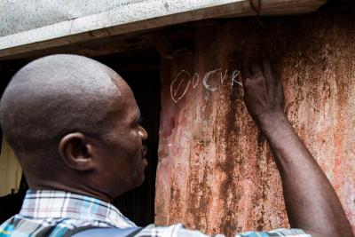 A man writes on the wall of a home to mark that they are vaccinated.