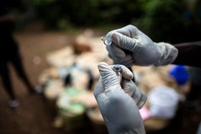 Someone wearing gloves opens a vial of the medicine