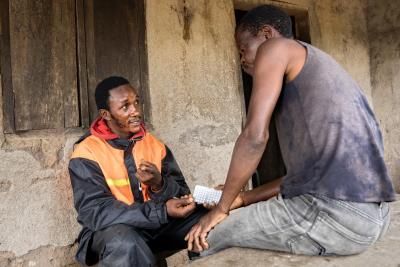 Two men sitting outside a house looking at medication