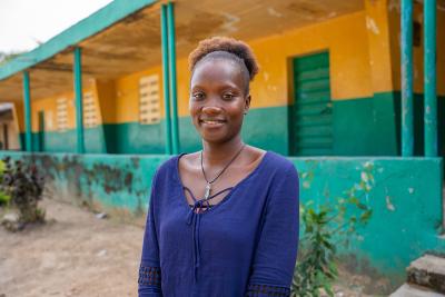 A young woman stands infront of a building