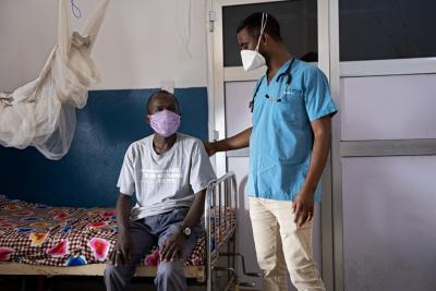 doctor standing next to patient sitting on hospital bed