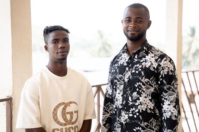 Two young men standing next to each other looking into the camera