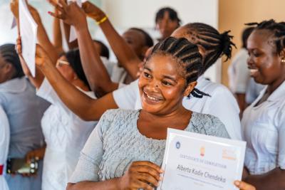woman holding certificate while others celebrate behind her