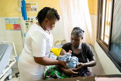 nurse is giving mother in hospital bed her newborn