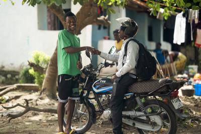 man standing greeting another man on a motorcycle 