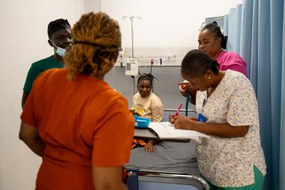 woman sitting in hospital bed surrounded by four clinicians