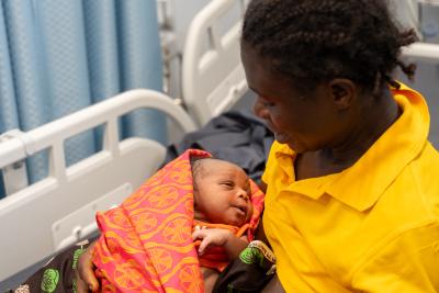 woman holding her baby sitting on hospital bed
