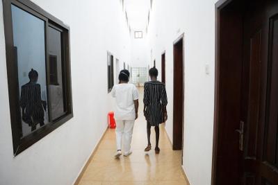 Mariama Koroma (pseudonym) (right) walks through the female ward at Lakka Government Hospital with Zainab Jalloh.