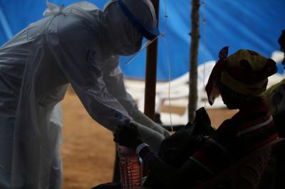 A person in a hazmat suit treats a patient