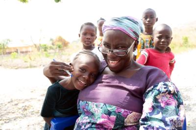 A woman is surrounded by kids.