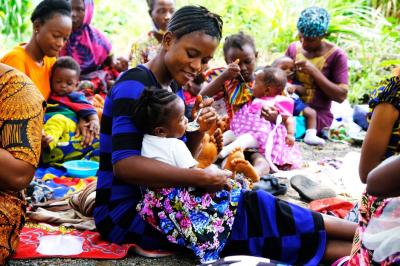 A group of mothers sit down and give their babies food.