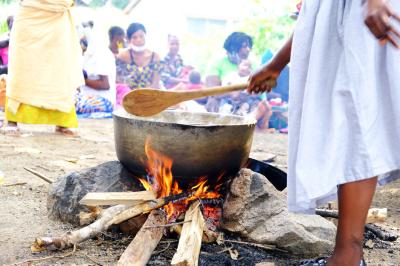 A woman prepares a big pot of Bennimix on a fire.