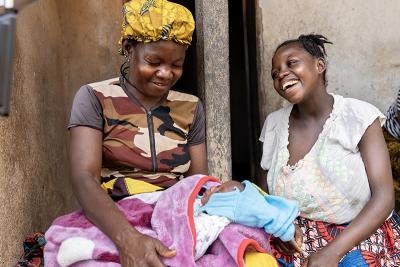 Two women sit and look at a new born baby