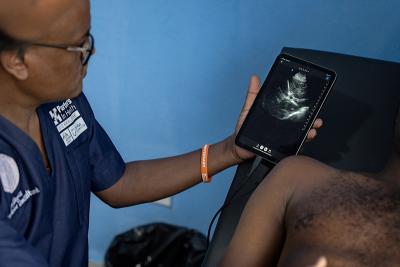 A doctor looks at a tablet while examining a patient