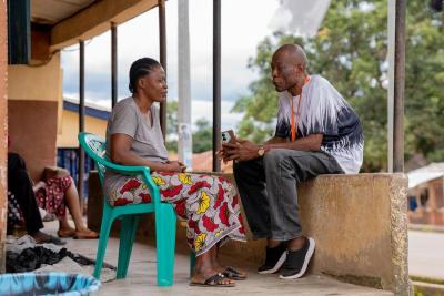 A man and woman sitting on a front porch in discussion with each other.